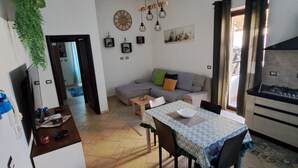 Una sala de estar con sofá, mesa de comedor y zona de cocina.