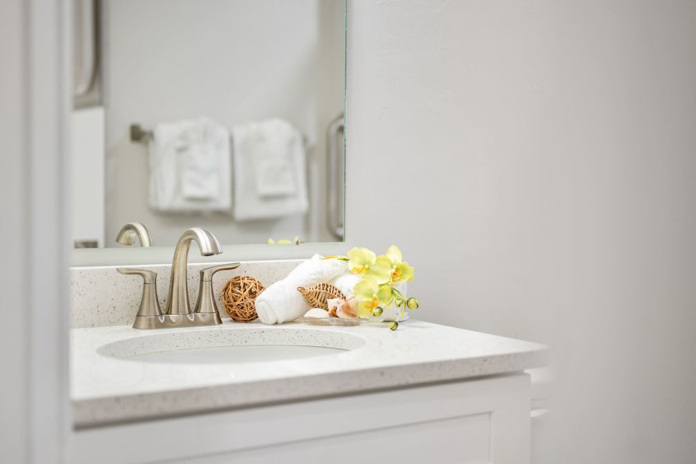 A bathroom with a white sink, a mirror, and a towel rack in the background.