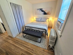 A bedroom with a bed, bench, and radiator.