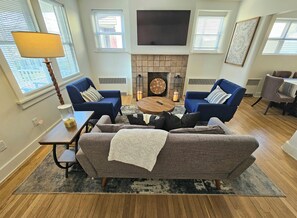 A living room with two sofas, a coffee table, a fireplace, and a TV mounted on the wall.