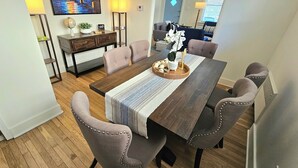 Un comedor con una mesa de madera, sillas acolchadas, un globo terráqueo, una planta y un cuadro en la pared.