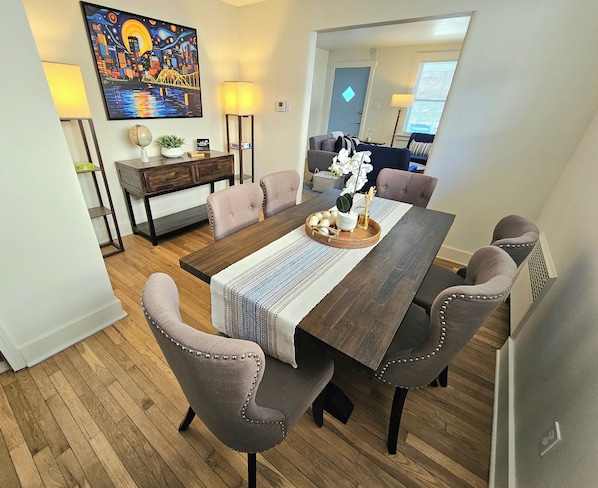 A dining area with a wooden table, cushioned chairs, a globe, a plant, and a painting on the wall.