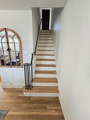 A staircase with wooden steps and a metal handrail, leading to a dark doorway.