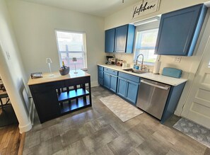 A modern kitchen with blue cabinets, a wooden island, and a stainless steel dishwasher.