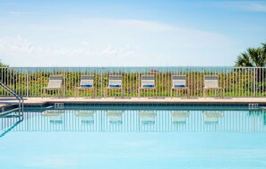 Ein Schwimmbecken mit Liegestühlen und einem Zaun.