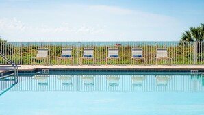Una piscina con sillas de descanso y una valla.