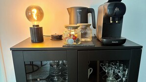 A black cabinet with a glass-fronted wine cooler, a coffee maker, and a light bulb on top. - Bright new T2 apartment next to the beach (Nice)