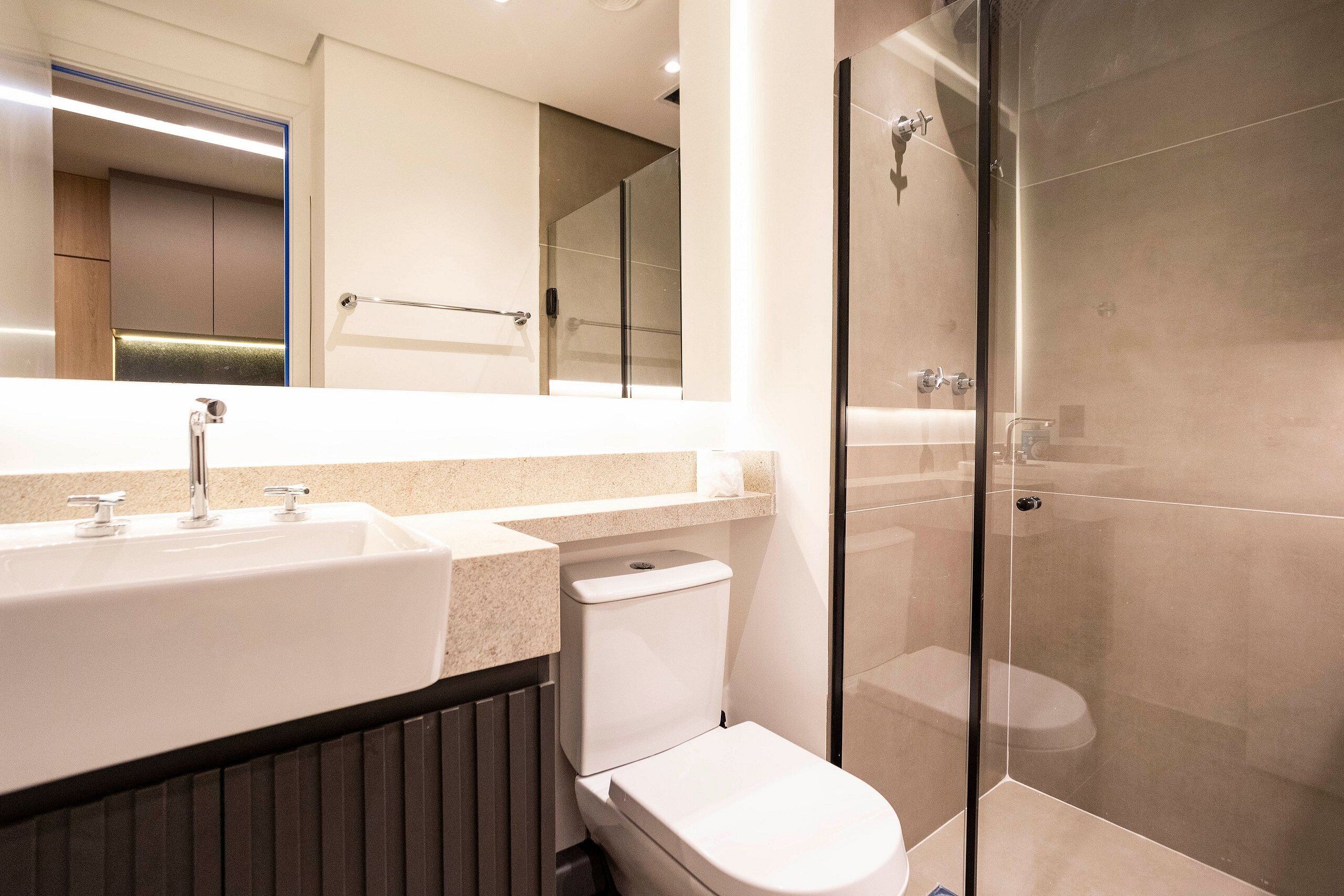 Un baño moderno con lavamanos, inodoro y cabina de ducha de vidrio.
