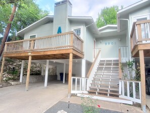 Ein zweistöckiges Haus mit einer Holzterrasse, einer Treppe und einer Steinmauer.
