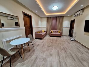Ein Wohnzimmer mit einem weißen Tisch, zwei Sofas, einer Deckenleuchte und einer Klimaanlage.