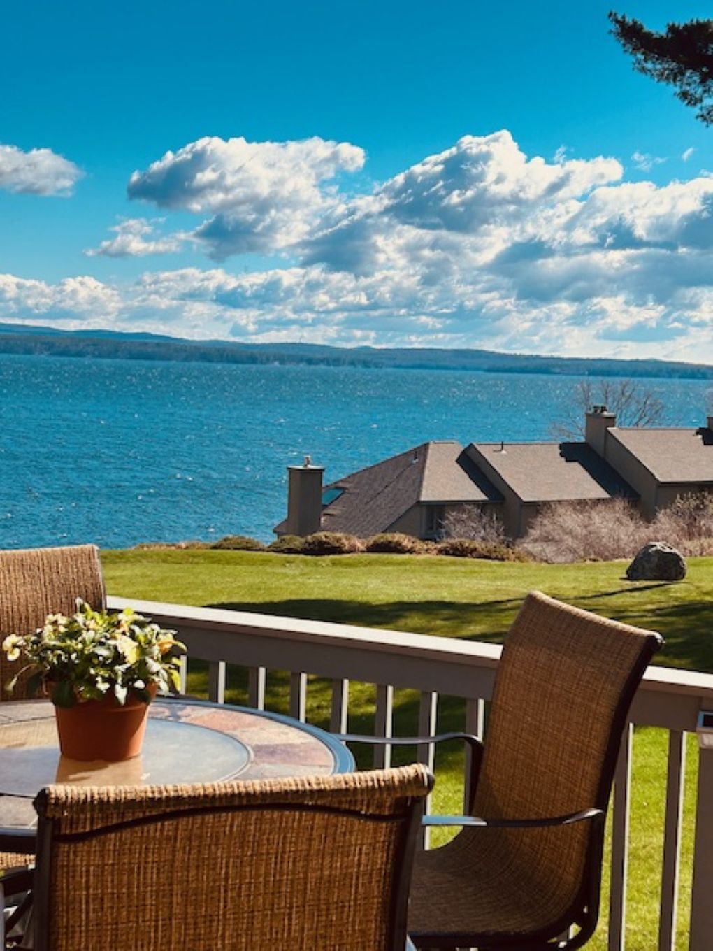 A terrace with a view of a body of water, a table, and chairs.