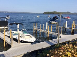 A marina with boats docked, wooden piers, and a forested island in the background.