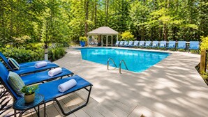 Un espace piscine comprenant des chaises longues, un gazebo et une terrasse en bois.