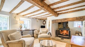Una sala de estar acogedora con vigas de madera a la vista, chimenea y asientos cómodos.
