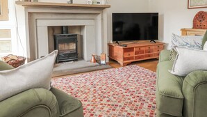 A living room with a fireplace, a television, and green furniture. - Vasey Croft (Keighley)