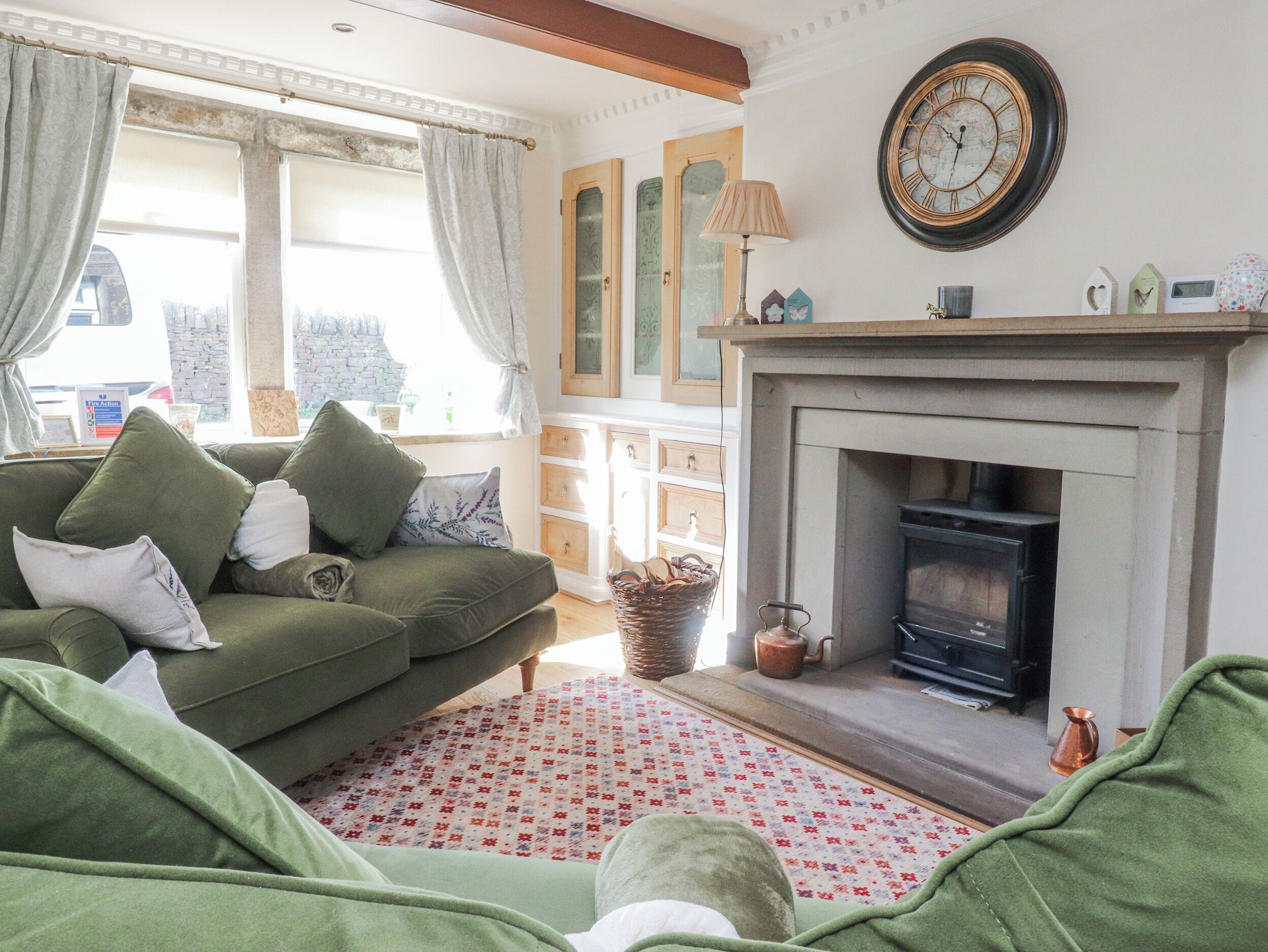 Una sala de estar acogedora con un sofá verde, una chimenea y un gran reloj de pared.