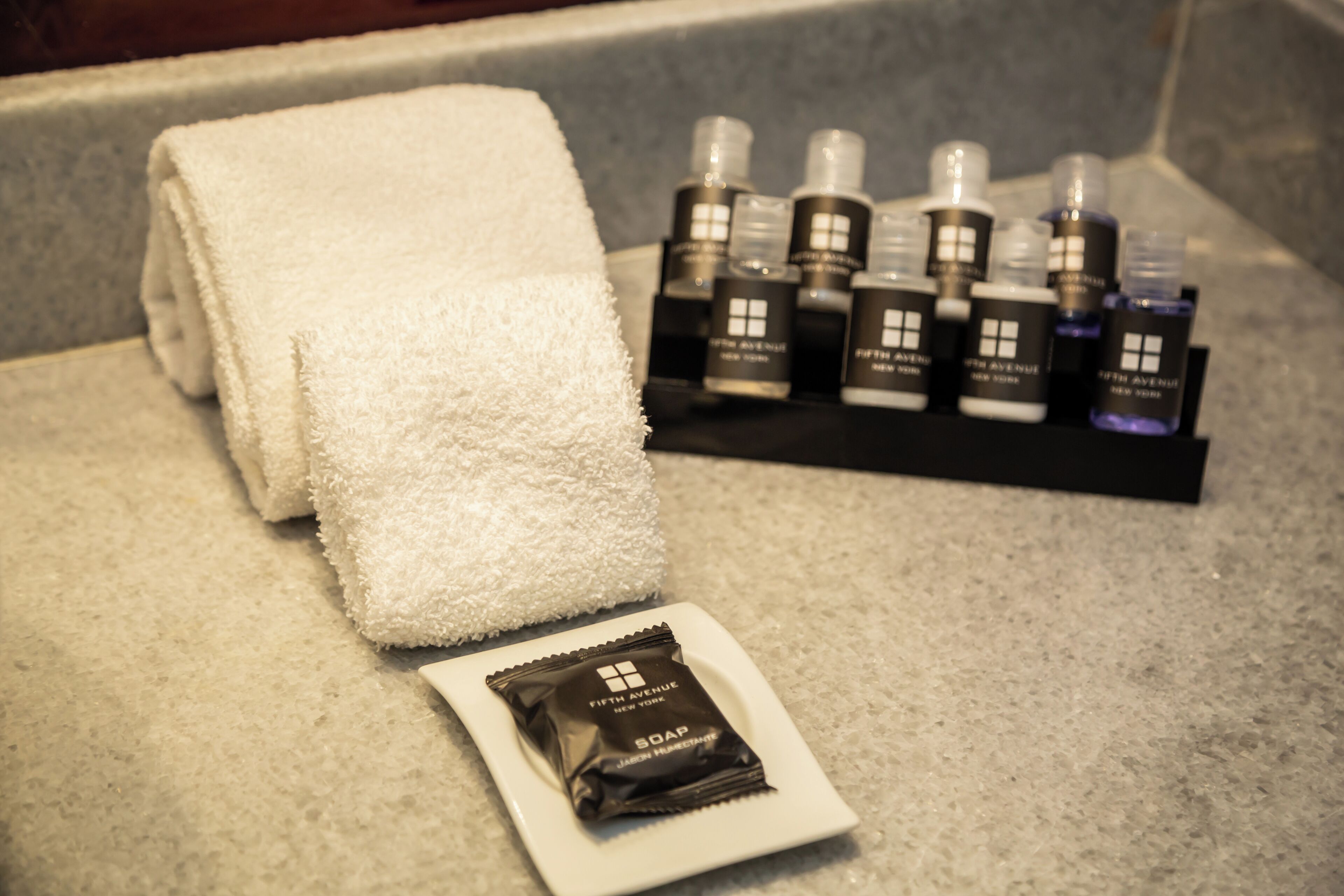 A bathroom with a towel, soap, and hand sanitizer on a countertop.