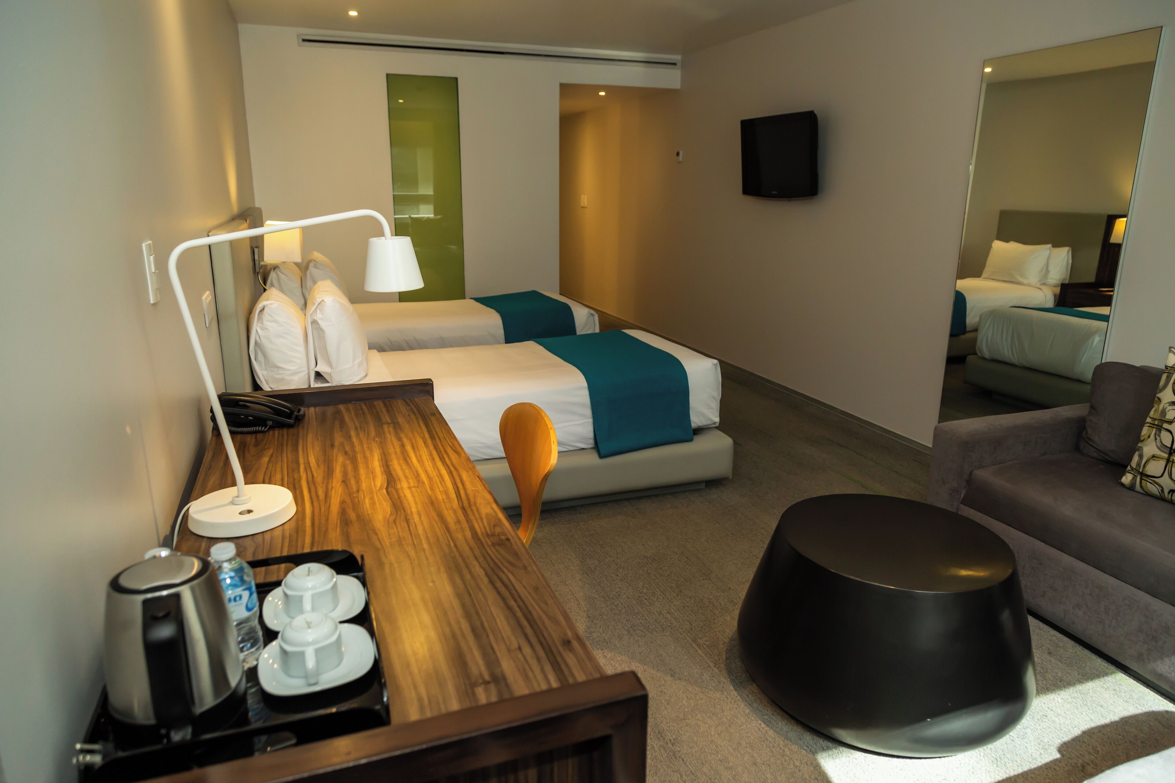 Une chambre d’hôtel avec deux lits, un bureau avec une lampe, une machine à café et un téléviseur.