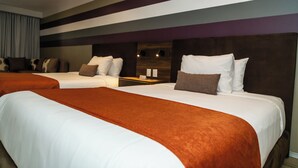 Habitación de hotel con dos camas, cabecera de madera y pared a rayas.
