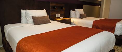 A hotel room with two beds, a wooden headboard, a nightstand, and a red accent wall.