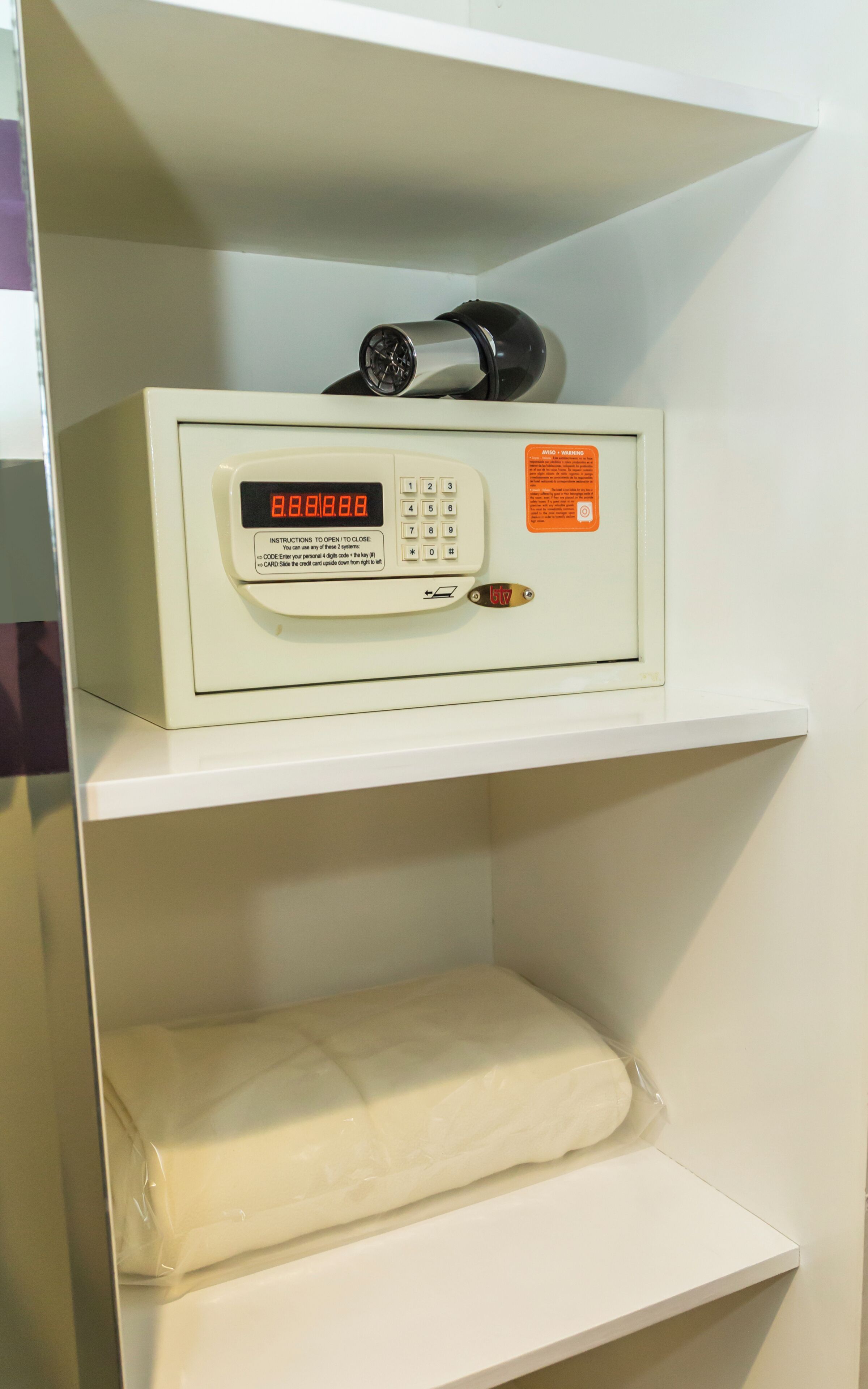 A white shelf with a white electronic device displaying '8888.8.8.8' and a warning label.