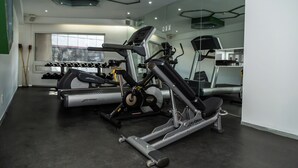 Un gimnasio con equipo de ejercicio, un ventanal grande y un espejo en la pared.