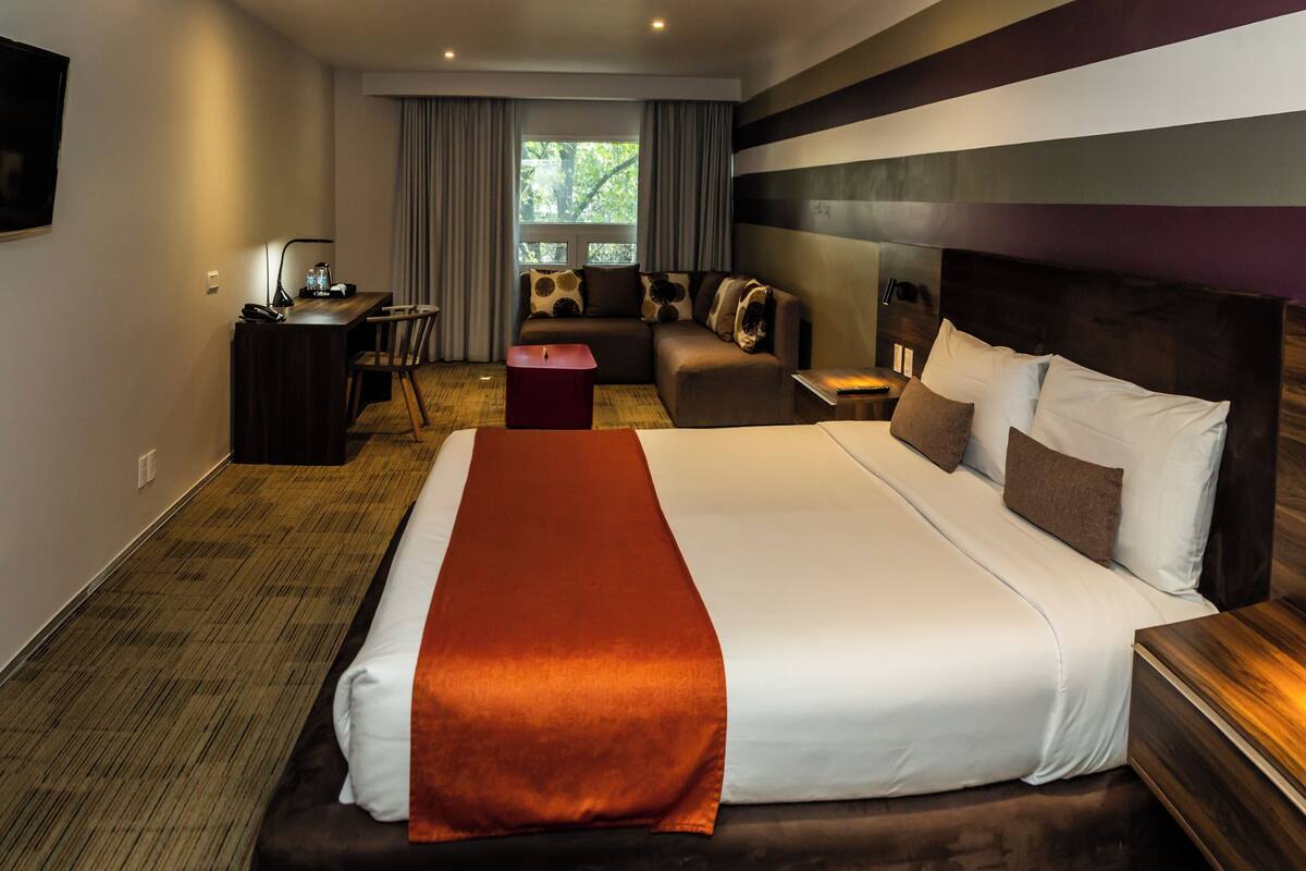 Una habitación de hotel con una cama grande, un escritorio, un sofá y un televisor.