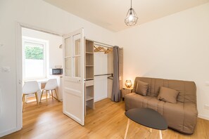 Un espace de vie compact comprenant un canapé, un coin repas avec des chaises, une kitchenette et une armoire.