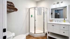 A bathroom with a toilet, a shower with a glass door, a sink with a mirror, and a towel rack. - Parkside Suite: Downtown Jacksonville (Jacksonville)
