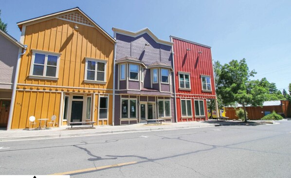 A row of colorful buildings with large windows and a clear street in front.