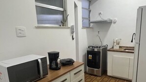 A compact kitchen with a microwave, coffee maker, and a small stove. - Cozy apartment - Copacabana (Rio de Janeiro)