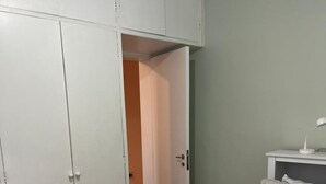 A bedroom with a bed, a nightstand, a wardrobe, and an open door leading to another room. - Cozy apartment - Copacabana (Rio de Janeiro)