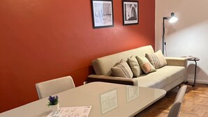 A room with a long table, two chairs, a sofa, and two framed pictures on the wall. - Cozy apartment - Copacabana (Rio de Janeiro)