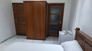Une chambre à coucher avec un lit, une armoire et un petit meuble blanc.
