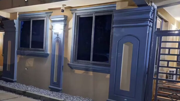 Un bâtiment doté de grandes fenêtres, d’une entrée fermée par un portail et d’un chemin en béton.