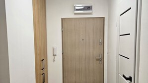 A hallway with a wooden door, a wall-mounted air conditioner, and a phone. - Malta View Prestige (Poznań)