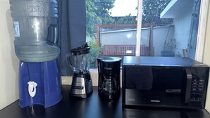 Una encimera de cocina con un dispensador de agua grande, una licuadora y un microondas.