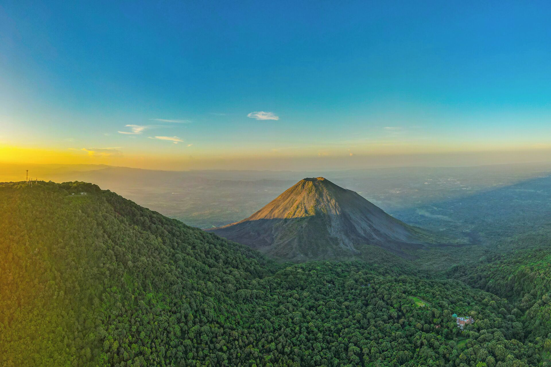 Una montaña con pico cónico rodeada de bosque denso.