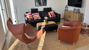 En moderne stue med sofa, to lænestole, sofabord og et fladskærms-tv.