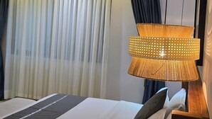 A hotel room with a bed, a bedside phone, a lamp, and a ceiling light. - Eza Hotel (Kigali)