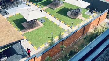 A rooftop terrace with a small garden, seating areas, and a water tank.