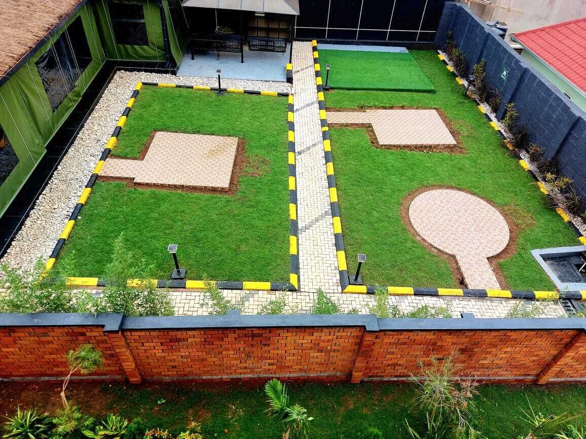 A courtyard with a green lawn, two tennis courts, and a brick wall.