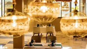 A restaurant with a marble floor, round tables, and hanging spherical chandeliers. - Eza Hotel (Kigali)