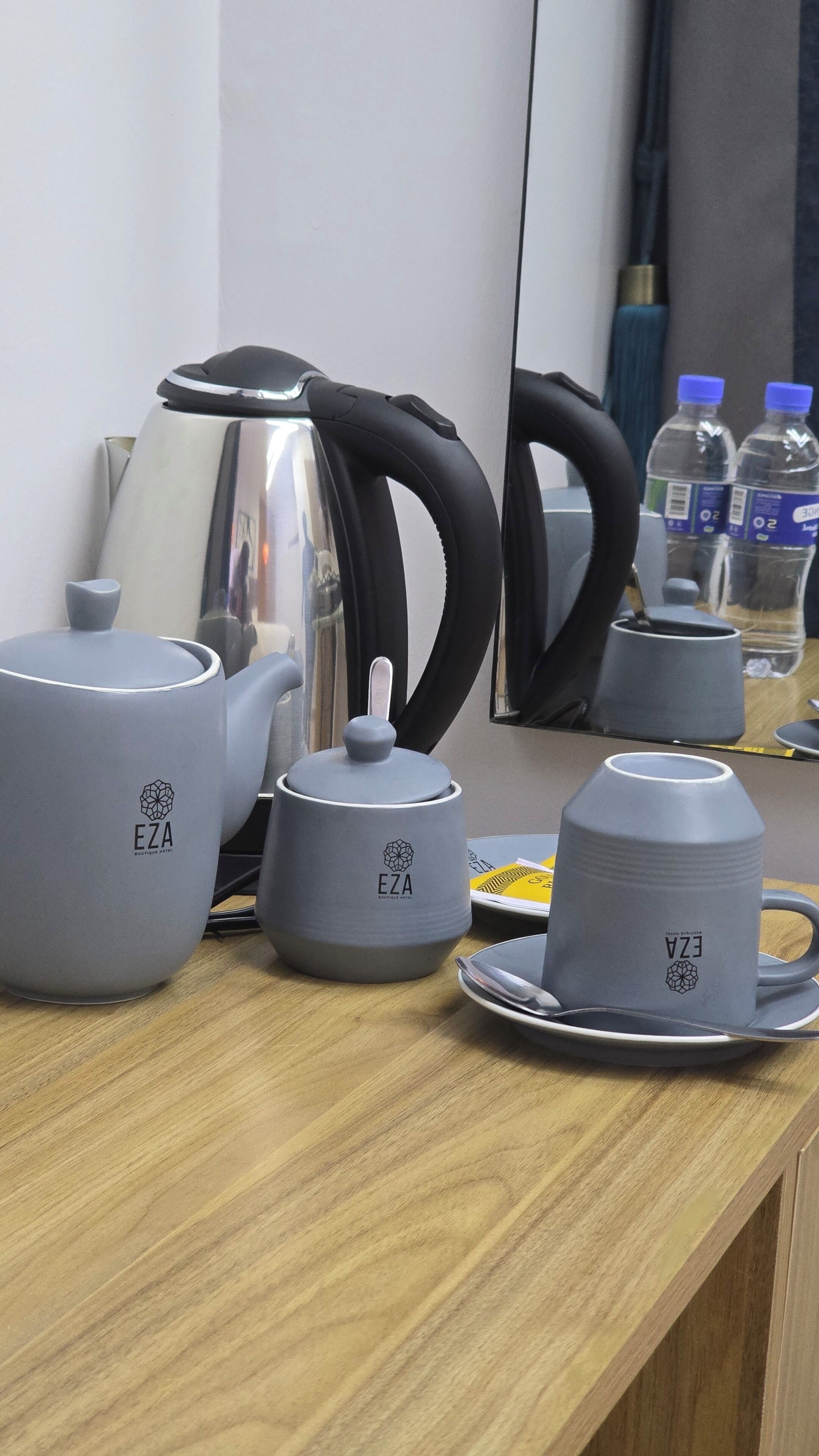 A kitchenette with a kettle, teapot, cups, and a water bottle.