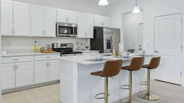 A modern kitchen with white cabinets, stainless steel appliances, and a central island with bar stools. - Kissimmee Oasis 4BR House Pool & Sleeps 8 (Kissimmee)