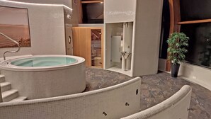 A spa area with a hot tub, a wooden door, a shower, and a potted plant. - Casa Rustica O Facho (Cangas)
