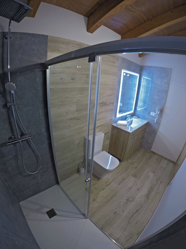 Une salle de bain moderne avec une douche à parois de verre, des toilettes et un lavabo avec un miroir.