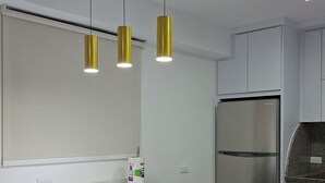 Une cuisine moderne dotée d’un îlot central, de luminaires suspendus, d’un réfrigérateur et d’un four à micro-ondes.