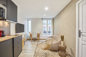 Ein kompakter Wohnbereich mit Küchenzeile, Essbereich und großem Fenster.
