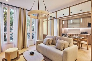 Ein modernes Wohnzimmer mit Sofa, Couchtisch und Essbereich mit Tisch und Stühlen.